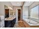 Bright bathroom featuring a soaking tub, walk-in closet, wood tile floors, and double sink vanity at 16736 Broadwater Ave, Winter Garden, FL 34787