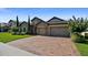 Charming stone home with a three-car garage, featuring a paved driveway and blossoming landscaping at 16736 Broadwater Ave, Winter Garden, FL 34787