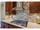 Close up of cooktop with stainless steel vent hood and tile backsplash at 16736 Broadwater Ave, Winter Garden, FL 34787