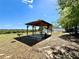 Community gazebo with picnic table, benches, and charcoal grill in open area with play area beyond at 2073 Newtown Rd, Groveland, FL 34736