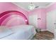 Vibrant pink bedroom with a rainbow wall, decorative lighting, and wood-look floors, offering a playful retreat at 2258 Crystal Falls Way, Orlando, FL 32824