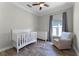 Bright Bedroom features a white crib, dresser, and comfy chair, complemented by wood-look tile floors at 2258 Crystal Falls Way, Orlando, FL 32824