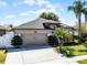 Beautifully landscaped home featuring a lush lawn, palm trees, and a two-car garage under a clear blue sky at 2258 Crystal Falls Way, Orlando, FL 32824