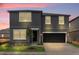 Modern two-story home with a gray exterior, black door and garage, and manicured lawn at twilight at 2306 Lancashire St, Davenport, FL 33896