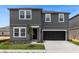 Modern two-story home with a gray exterior, black door and garage, and manicured lawn at 2306 Lancashire St, Davenport, FL 33896