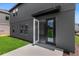 Modern home exterior featuring gray siding, an open doorway to the bright living space, and a well-maintained lawn at 2306 Lancashire St, Davenport, FL 33896