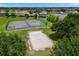 Aerial view of community tennis and sand volleyball courts nestled among green spaces and residential homes at 2306 Lancashire St, Davenport, FL 33896