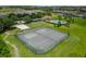 Aerial view of community tennis courts, sand volleyball court, pool and clubhouse amidst lush landscaping at 2306 Lancashire St, Davenport, FL 33896