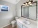 Well-lit bathroom showcasing mosaic-trimmed mirror, white vanity, toilet, and a window at 2350 Blue Sapphire Cir, Orlando, FL 32837