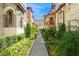 Picturesque walkway lined with manicured landscaping between tan townhomes under a bright blue sky at 316 Trieste Loop, Lake Mary, FL 32746