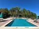 Community swimming pool with lounge chairs, tables, umbrellas and pergola seating area at 413 Summit Ridge Pl # 115, Longwood, FL 32779