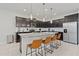 Modern kitchen featuring dark wood cabinets, granite countertops, stainless steel appliances, and an island with bar stool seating at 4321 Lana Avenue, Davenport, FL 33897