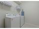 Laundry room with a white Whirlpool washer and dryer, including an ironing board and a wire rack for storage at 4321 Lana Avenue, Davenport, FL 33897