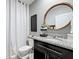 Bathroom with granite vanity, oval mirror, toilet with step stool, and a white shower curtain at 460 Lily Ln, Davenport, FL 33837