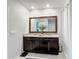 Bathroom featuring a double sink granite vanity and a framed mirror; the shower is curtained off at 460 Lily Ln, Davenport, FL 33837