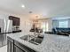 Modern kitchen island with stainless steel sink, granite countertop, and view of the dining area at 460 Lily Ln, Davenport, FL 33837