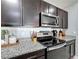 Well-equipped kitchen featuring dark cabinets, granite countertops, stainless steel microwave and oven at 460 Lily Ln, Davenport, FL 33837