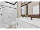 Modern bathroom featuring double sinks, wood accent wall, and a sleek glass-enclosed shower with black fixtures at 4955 Castle E St, Kissimmee, FL 34758