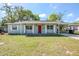 Charming one-story home featuring a brick facade, a bright red front door, and a covered carport at 5210 Grandview Dr, Orlando, FL 32808