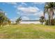 Expansive backyard with lush lawn and mature palm trees overlooking a serene lake at 5790 Crystal Beach Rd, Winter Haven, FL 33880