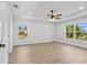 Bright main bedroom with wood flooring, tray ceilings, ceiling fan, and large windows offering outdoor views at 5790 Crystal Beach Rd, Winter Haven, FL 33880