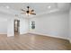 Bright main bedroom with wood flooring, tray ceiling, ceiling fan, and a large closet visible through an open door at 5790 Crystal Beach Rd, Winter Haven, FL 33880