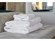 Close up of clean, white towels folded and set on a bench at the foot of the bed, mirror on the wall at 6165 Carrier Dr # 3512, Orlando, FL 32819