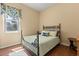 Cozy bedroom featuring hardwood floors, a decorative metal bed frame, and a window at 6651 Sylvan Woods Dr, Sanford, FL 32771