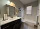 Bright bathroom featuring a vanity with dark wood cabinets and a tub with tiled walls at 938 Cherry Valley Way, Orlando, FL 32828