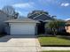 Charming single-story home showcasing a well-manicured lawn, and a two car garage on a sunny day at 938 Cherry Valley Way, Orlando, FL 32828