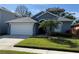 Charming single-story home showcasing a well-manicured lawn, and a two car garage on a sunny day at 938 Cherry Valley Way, Orlando, FL 32828