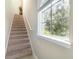 Bright staircase with carpeted steps, white railing, and natural light from a window at 12849 Bovet Ave, Orlando, FL 32827