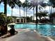 Community pool with palm trees has lounge chairs and umbrellas for relaxing near the water at 225 Vestrella Dr, Kissimmee, FL 34759