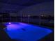 Outdoor pool illuminated with blue lights, featuring a dolphin mosaic at night at 252 Julliard Blvd, Davenport, FL 33897