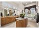 Bright bathroom featuring dual vanities, granite counters, tiled floors, and large soaking tub under shuttered windows at 401 Timberwalk Ln, Lake Mary, FL 32746