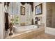 Sunlit bathtub underneath shuttered windows framed with decorative valances and framed artwork at 401 Timberwalk Ln, Lake Mary, FL 32746