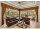 Elegant living room with tile floors, two leather sofas, coffered ceiling, and large windows overlooking pool at 401 Timberwalk Ln, Lake Mary, FL 32746