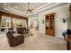 Open living room with a coffered ceiling, tile floors, brown leather sofas, and an elegant wooden display cabinet at 401 Timberwalk Ln, Lake Mary, FL 32746