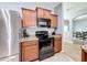 Well-equipped kitchen featuring stainless steel appliances, sleek black stovetop, granite countertops, and wooden cabinets at 673 Highland Meadows Ave, Davenport, FL 33837