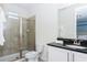 Bathroom features a glass-enclosed shower, tiled walls, and a black granite countertop with white cabinets at 7463 Marker Ave, Kissimmee, FL 34747