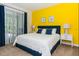 Bedroom with a yellow accent wall, matching lamps, large window and a cozy queen bed at 7463 Marker Ave, Kissimmee, FL 34747