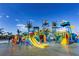 Colorful water park features slides, splash zones, palm trees, and a sign that reads 