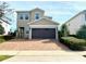 Charming two-story home with neutral colors, lush landscaping, and a brick driveway at 7479 Marker Ave, Kissimmee, FL 34747