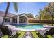 Inviting pool is flanked by lounge chairs, artificial turf, and a screened in porch for ultimate relaxation at 768 Park Valley Cir, Minneola, FL 34715