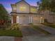 Charming two-story home features a spacious two-car garage and a beautifully illuminated exterior at twilight at 8312 Fontera Dr, Davenport, FL 33896