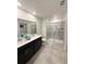 Modern bathroom featuring a dual sink vanity and a walk-in shower with tiled walls at 945 Laurel View Way, Groveland, FL 34736