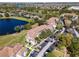 Aerial view of condo buildings with terracotta roofs, surrounded by a lake, trees, and parking at 13929 Fairway Island Dr # 825, Orlando, FL 32837