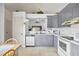 Bright kitchen with gray cabinets, white appliances, and an open view to the dining area at 165 Coralwood Cir, Kissimmee, FL 34743