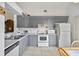 Bright kitchen featuring gray cabinets, white appliances, and tile flooring at 165 Coralwood Cir, Kissimmee, FL 34743