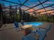 Relaxing screened-in pool area illuminated at dusk with comfortable seating near a cozy fire pit at 1659 Cherry Blossom Ter, Lake Mary, FL 32746